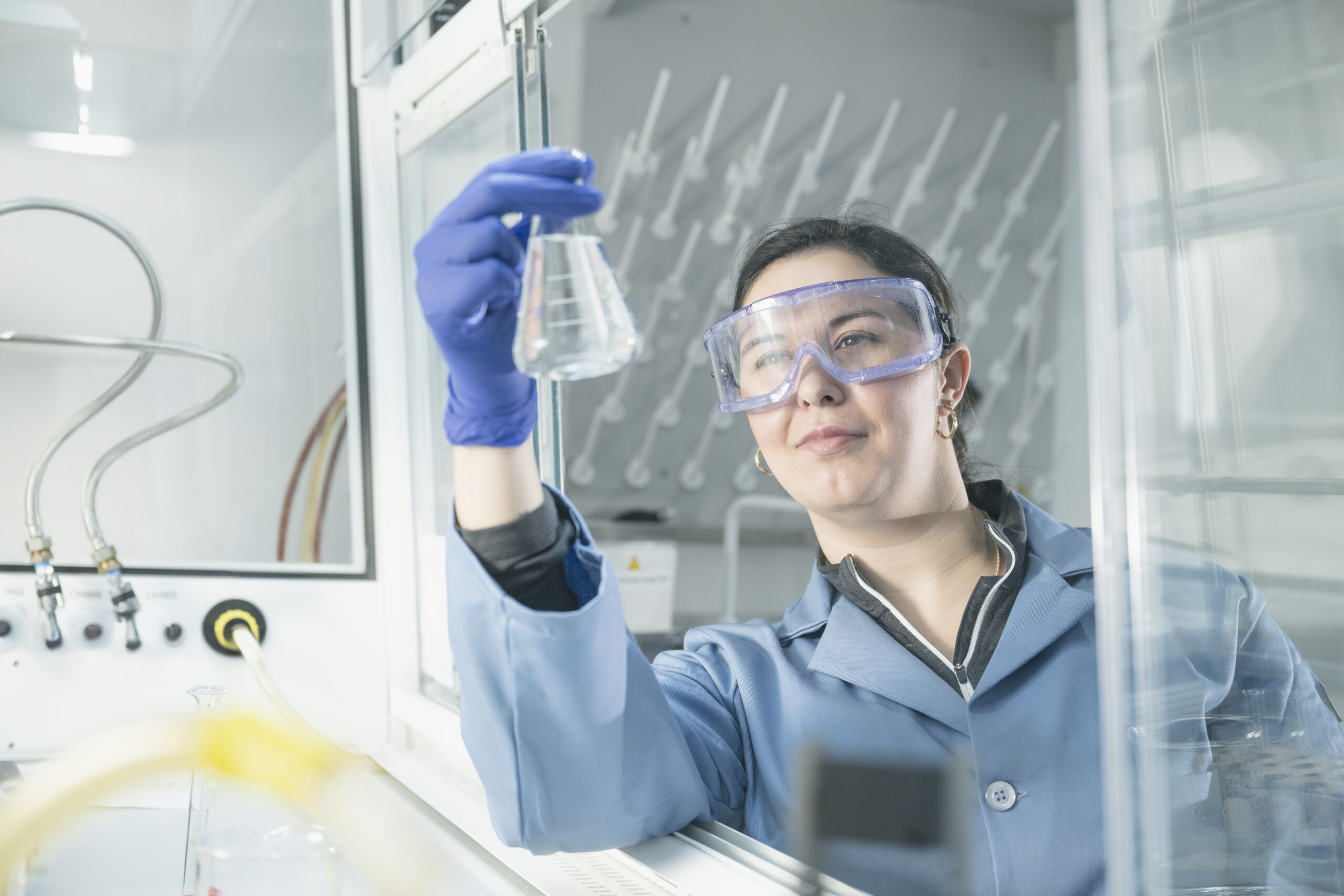 _CJ90482 Pharmacy female student working in a lab looking at liquid in beeker.