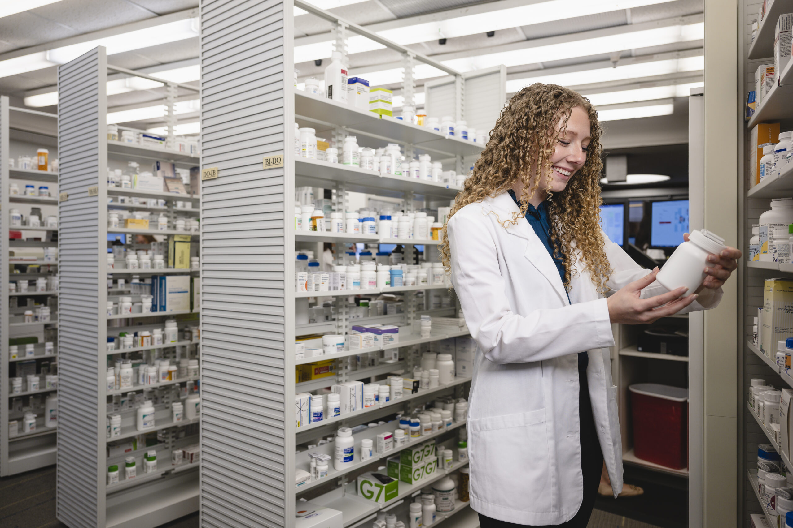 CJ9_7784 Student working in pharmacy. Reading a label on a bottle of medication.
