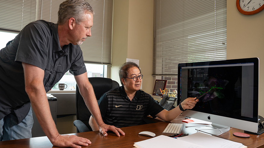 Mark Hall and Zhong-Yin Zhang view a molecular structure on a large computer screen.