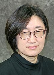 Headshot of Yoon Yeo. She wears a black dress shirt in front of a gray photo backdrop.