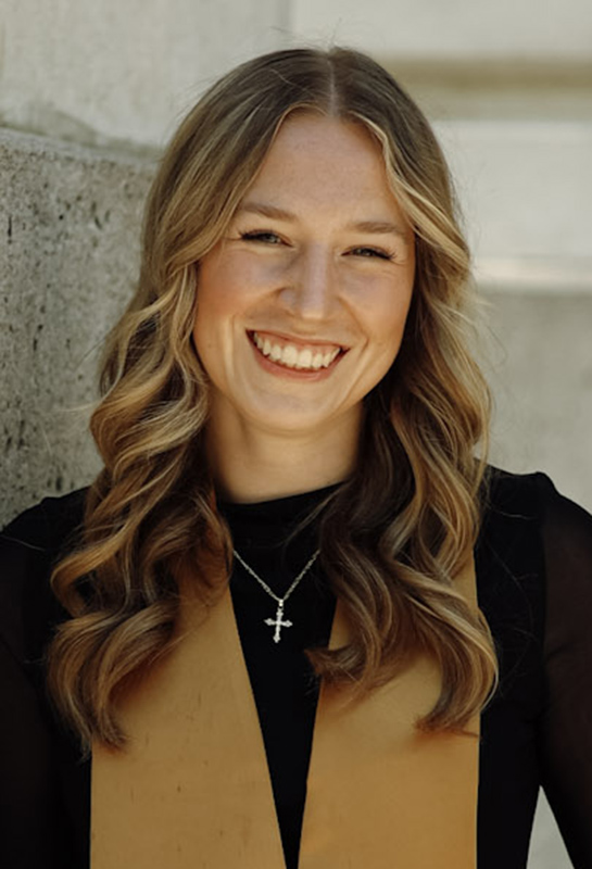 Headshot of Olivia Lawrence smiling for the camera wearing a black shirt with gold scarf.